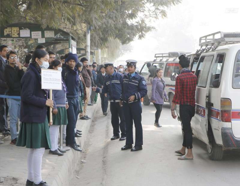 Traffic police with the support of school children requesting passengers to remain in queue for boarding buses at Bhrikutimandap, Kathmandu in Tuesday. Photo: Pradip Luitel/Aarthik Abhiyan