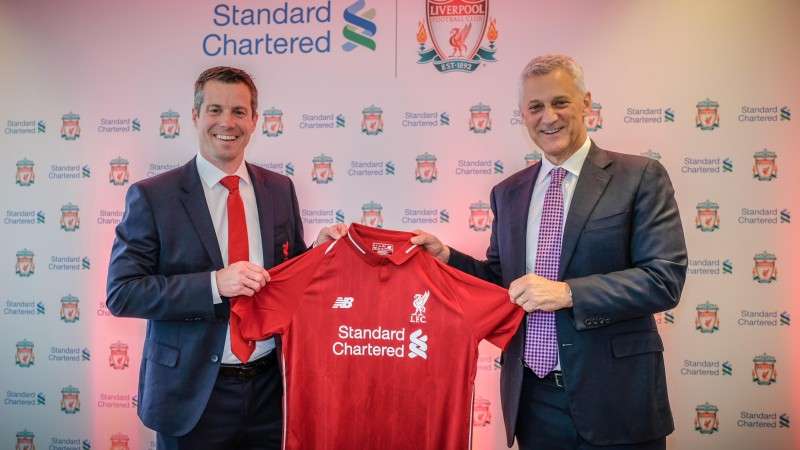 This handout photo shows Billy Hogan, MD and Chief Commercial Officer of Liverpool Football Club, and Bill Winters, CEO of Standard Chartered Bank unveiling a jersey of Liverpool FC after extending their sponsorship deal for the next four season.