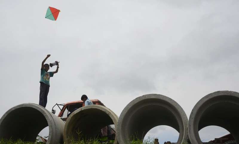 A child attempts to fly a kite by standing on top of a hume pipe in Teku. Photo: Ravi Maharjan/NBA