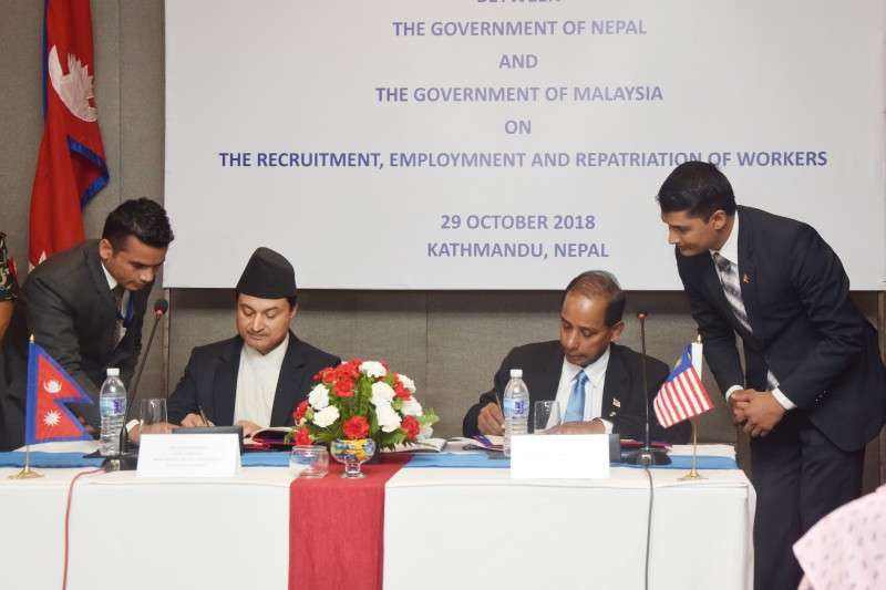 Minister for Labour, Employment and Social Security Gokarna Bista (L) and Malaysia’s Minister of Human Resources M Kula Segaran sign labour agreement on behalf of their respective governments in Kathmandu, on Monday, October 29. Nepali migrant workers opting to work in Malaysia will not have to pay airfare and visa fee, according to the agreement. Photo: NBA