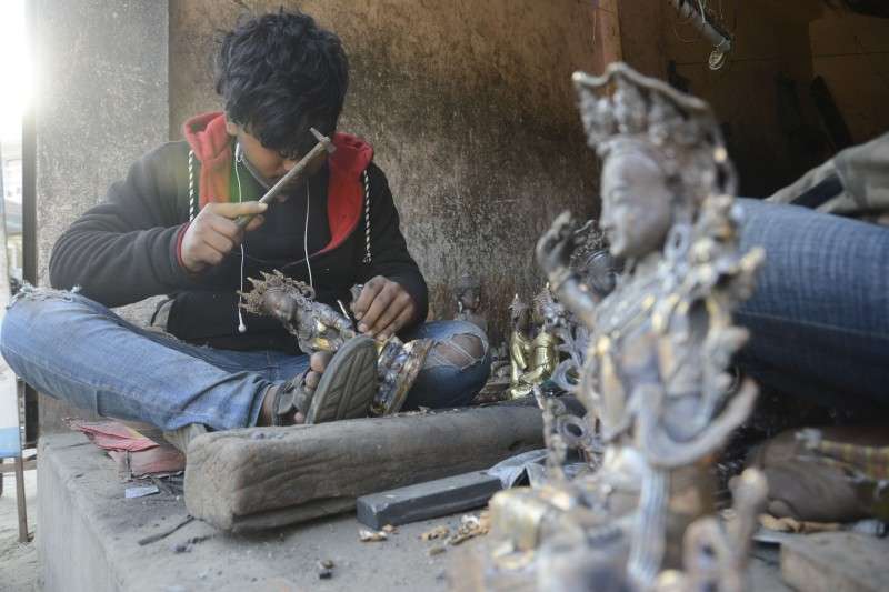 A craftsman making a statue of Buddha in Chyasal. Lalitpur. The craftsman says he earns Rs 15,000 from one such statue and in average he completes four statues a month. Photo: Ravi Maharjan/NBA