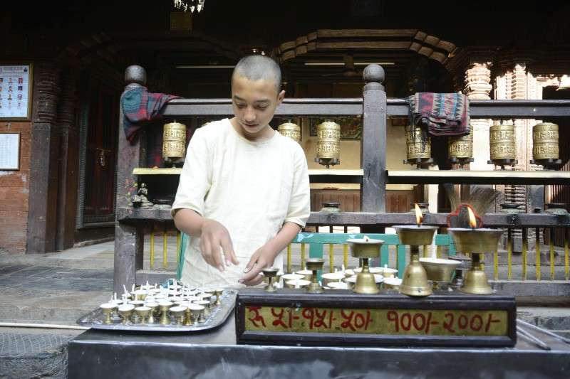 The priest of Lalitpur-based Golden Temple preparing to sell butter lamps on the temple premises. The locals say that the priest of this Buddhist shrine gets changed every month. Photo: Ravi Maharjan/NBA
